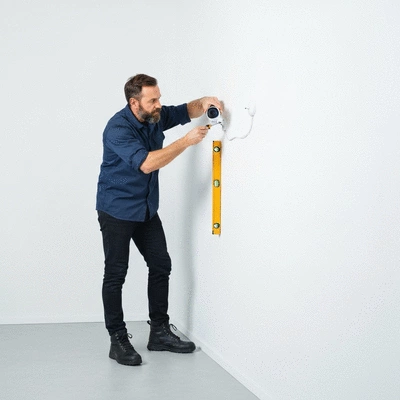 Professional electrician installing a security camera on a wall